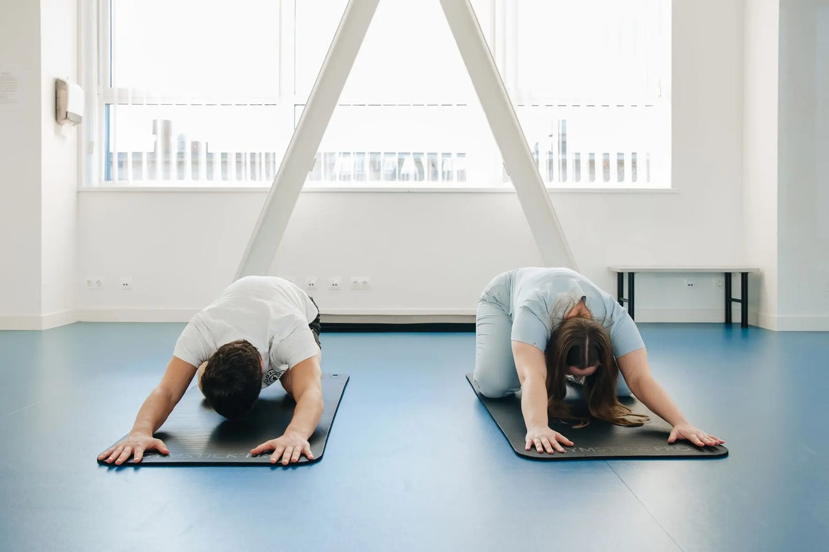 Two individuals practicing yoga in a modern clinic setting, focusing on relaxation and therapy.