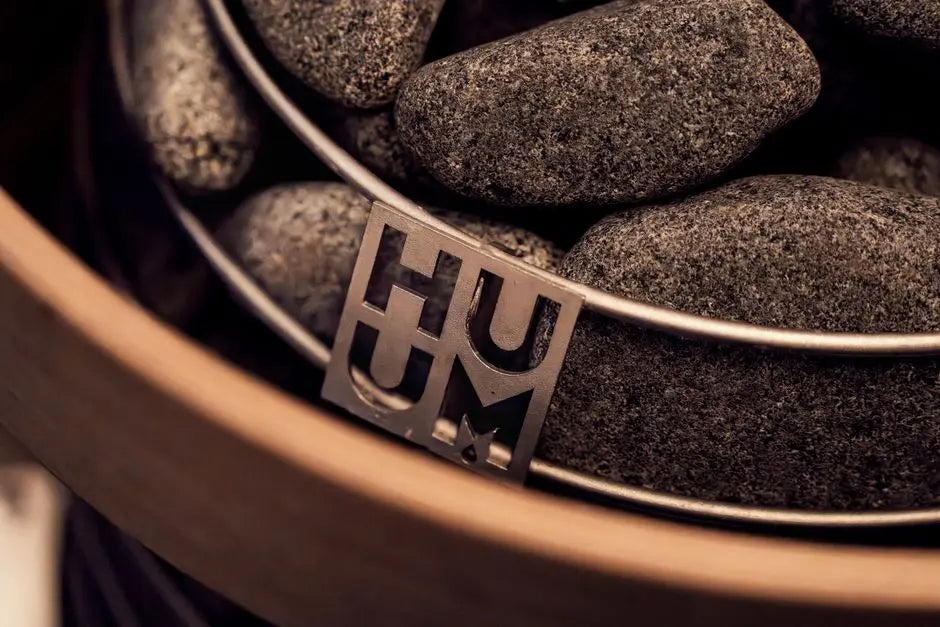 Stylish modern sauna heater with stones, featuring HUUM logo, ideal for spa or wellness settings.