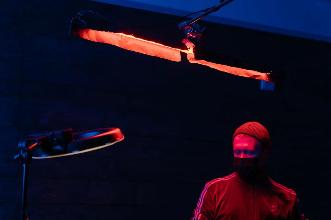 Tattoo artist working under moody red and blue neon lights in a studio.