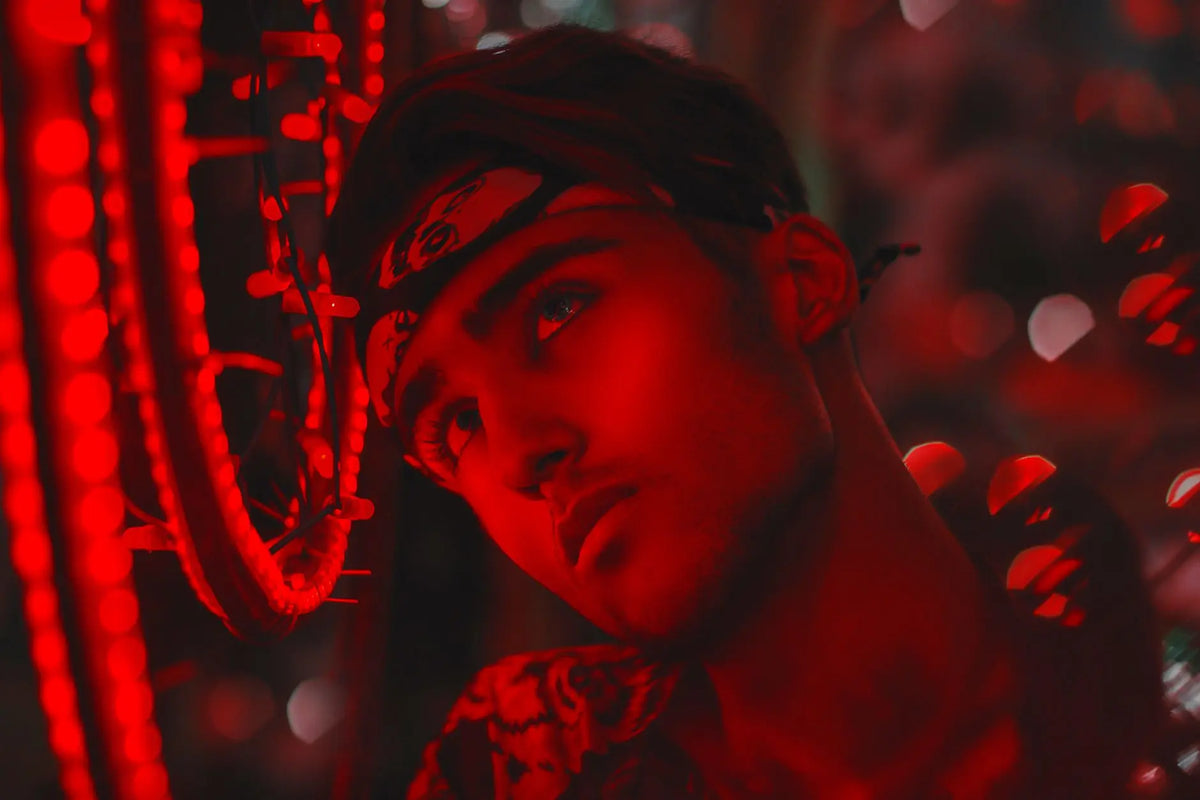 A striking portrait of a young man adorned with neon lights and vivid red tones, creating a mysterious, dreamlike effect.