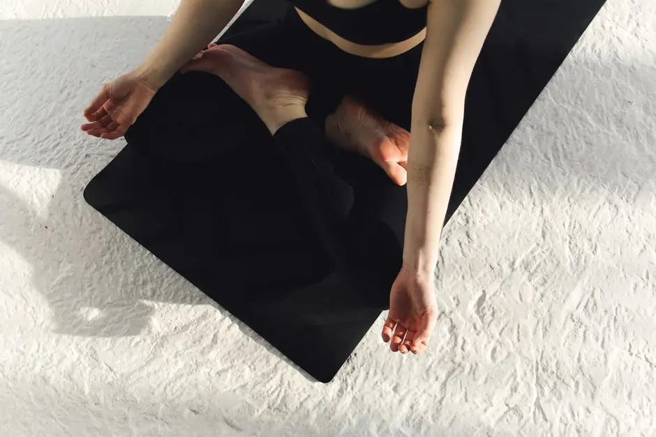 A person meditating in a peaceful pose on a black yoga mat, representing mindfulness and tranquility.