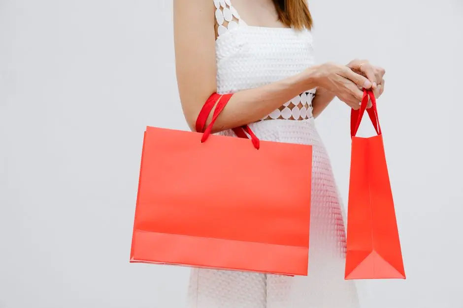 Stylish woman holding vibrant red shopping bags, dressed in a white dress, perfect for retail themes.