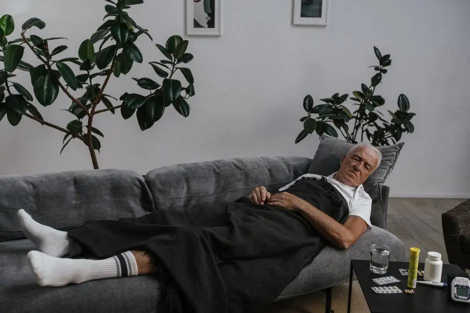 Elderly man resting on sofa with medical supplies nearby, surrounded by houseplants.